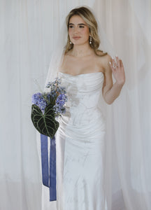 Notable contemporary two-piece wedding look made of lux Italian silk. The corset features a cinched waist and draped neckline inspired by the classic ball gown and a boned corset with a zipline on the back. The corset is doubled, with an additional shaping corset sewn in. The look is finished with a flowy skirt with a midi train reminiscent of ancient Greek statues.