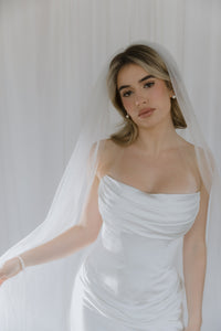 Notable contemporary two-piece wedding look made of lux Italian silk. The corset features a cinched waist and draped neckline inspired by the classic ball gown and a boned corset with a zipline on the back. The corset is doubled, with an additional shaping corset sewn in. The look is finished with a flowy skirt with a midi train reminiscent of ancient Greek statues.