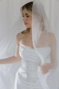 Notable contemporary two-piece wedding look made of lux Italian silk. The corset features a cinched waist and draped neckline inspired by the classic ball gown and a boned corset with a zipline on the back. The corset is doubled, with an additional shaping corset sewn in. The look is finished with a flowy skirt with a midi train reminiscent of ancient Greek statues.